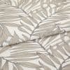 Folded curtain fabric with taupe botanical leaf print, linen-like texture, partially overlapped; close-up studio view showing neutral tones and soft, even lighting.