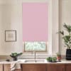Pink roller blind covers a window above a stainless sink, blocking light; kitchen counter holds a faucet, black bowl of greens, dish towel, potted herbs and a tall plant, wooden cabinets below.