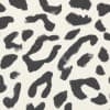 Irregular black brushstroke spots scatter across an off-white, textured fabric background, forming a loose, abstract leopard-print pattern with visible brush marks and varying spot sizes.