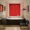 Red horizontal blinds centered over a window, fully closed and dimming light; above a white oval bathtub in a warmly lit striped-wood bathroom with sink, mirror, shelf and chair.