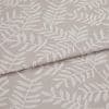 Beige jacquard fabric with raised white fern motif; folded and overlapped; close-up of an upholstery/curtain sample on a flat surface under soft, neutral lighting.