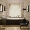 Beige roller blind over window — fully lowered, diffusing soft daylight — above a dark-wood inset bathtub in neutral striped-wall bathroom with vessel sink, floating shelf, chair and warm tile flooring.