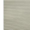 Beige honeycomb (cellular) blind with horizontal pleats and visible hexagonal cell ends at left, fully lowered and closed, blocking light; close-up filling the frame against a neutral, studio-lit background.