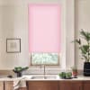Pink roller blind covers most of a kitchen window, filtering daylight; stainless faucet and double sink below, wood cabinets, countertop with bowls of leafy greens, potted plants, framed sketch.