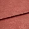Folded rose‑colored textured fabric, a soft velvet-like material with a horizontal overlap fold; lit evenly in a close-up studio view showing subtle sheen and woven surface detail.