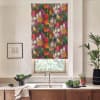 Floral roller blind covers window, displaying dense multicolored tulip pattern; kitchen sink and faucet sit below on marble countertop with bowls of greens, potted plants, and framed sketch on wall.