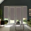 French glass doors with four mauve roller blinds lowered halfway, framing a sunlit garden; glass coffee table and zigzag rug sit between two green armchairs in a contemporary living room.