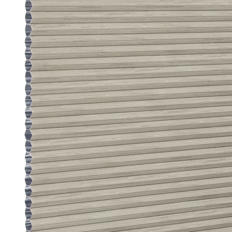 Beige honeycomb cellular window blind with pleated horizontal ribs and exposed left-edge cells — fully lowered and closed, blocking view; close-up fills frame in neutral, even lighting.