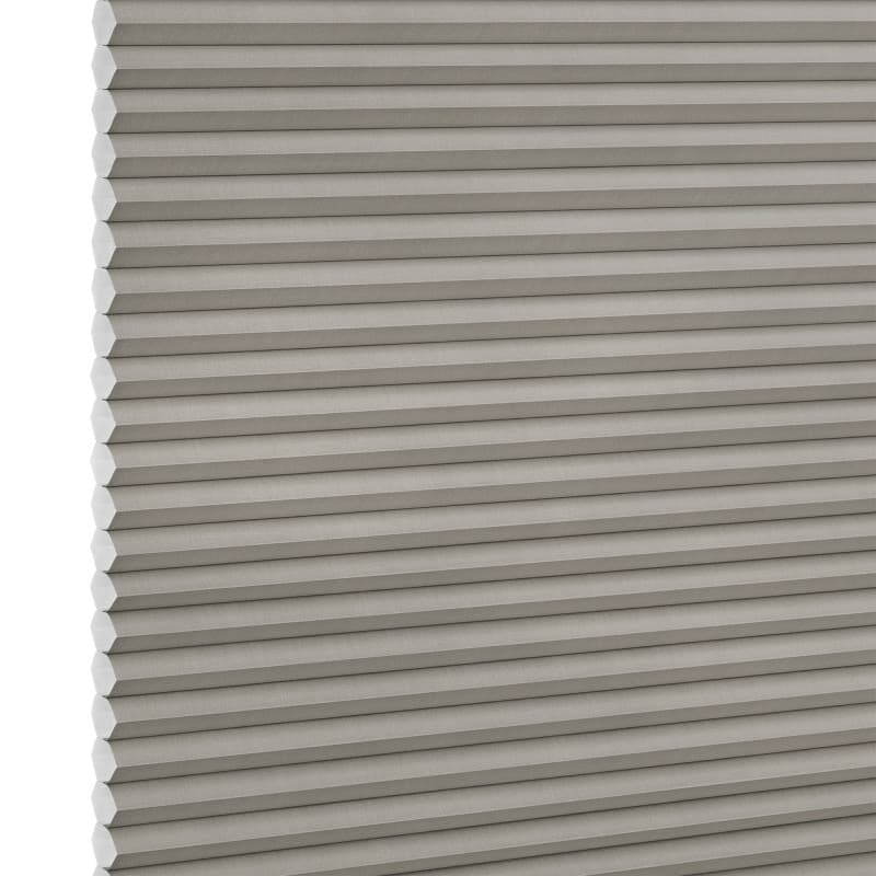 Grey honeycomb (cellular) blind, fully lowered with visible hexagonal cells along the left edge, blocking light; close-up product shot with even lighting and white background.