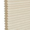 Honeycomb cellular blind, beige pleated fabric with visible hexagonal cell edges at left; closed and flat. Close-up against a neutral white background with soft, diffused indoor lighting.