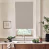 Gray roller blind covers window above a faucet and double sink; countertop displays black bowl of greens, potted plants, towel draped over wooden cabinets and framed sketch on wall.