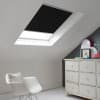 Room with white eaves wall, dark blue-grey wall to right with a shabby chic white drawer unit, a contemporary white chair, white painted floorboards and a skylight blind in black.