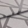 Textured light-grey fabric with dark-grey intersecting geometric bands (raised weave), folded once to reveal the edge; close-up studio-lit view highlighting weave, pattern and subtle sheen on a neutral surface.