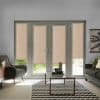 Beige roller blinds cover four tall French-style patio doors and sidelights, mostly lowered and filtering soft daylight into a modern living room with gray sofas, glass coffee table, and chevron rug.