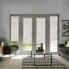 White patterned roller blinds on central French doors and sidelights, lowered to filter daylight and reveal a lawn strip beneath; living room with grey seating, coffee table and chevron rug.