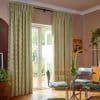 Floor-length green-and-cream checkered curtains on a rod over patio doors, drawn aside, filtering light and framing an open glass door in a sunny dining nook with table, chairs and plants.