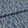 Blue woven fabric with cream embroidered wavy rope pattern, folded over itself, shown in a close-up studio view with soft, even lighting.