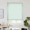 Mint-green pleated blind, fully lowered and filtering daylight; in a white-walled dining nook with round table topped by a glass vase of daisies, carafe and glasses, plus a fiddle‑leaf fig.