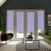 French glass doors with four narrow sidelights, fitted with lavender roller blinds partially lowered, facing a sunlit garden; modern living room with green armchairs, glass coffee table on chevron rug.