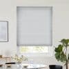 Light-gray pleated cellular blind, fully lowered across the window with horizontal texture, filtering soft daylight into a dining nook with table, glassware, vase of flowers and a fiddle-leaf fig.