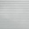 Horizontal pleated (cellular) blind, fully lowered with regular narrow folds and textured fabric, blocking the view and softly diffusing daylight in a neutral, evenly lit interior.