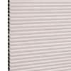 Cellular pleated window shade (honeycomb design) fully lowered, pale blush fabric with visible black cell openings at left edge, blocking light; close-up view against a neutral background.