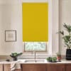 Yellow roller blind covers kitchen window above a sink; faucet and basin sit on a marble countertop with bowls of leafy greens, potted plant and framed sketch.