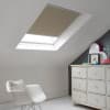 Room with white eaves wall, dark blue-grey wall to right with a shabby chic white drawer unit, a contemporary white chair, white painted floorboards and a skylight blind in taupe.