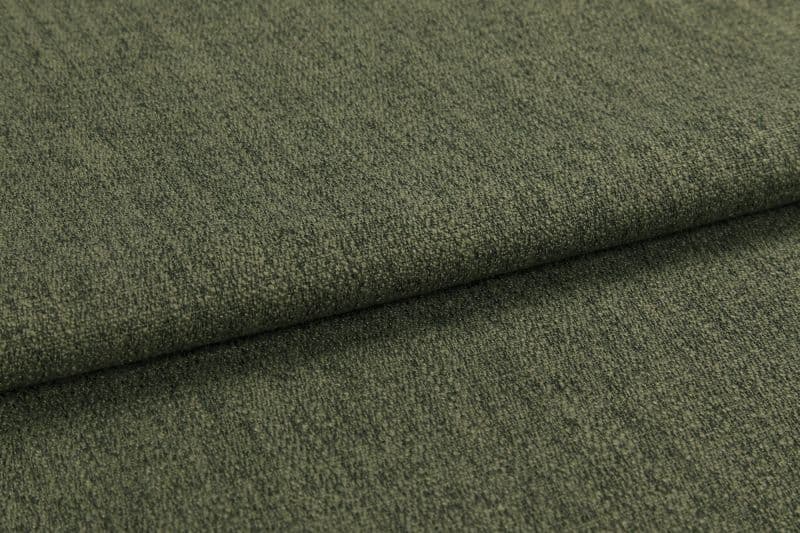 Olive-green textured upholstery fabric, folded once creating an overlapping edge; tightly woven, slightly napped surface; photographed in a close-up, evenly lit studio setting emphasizing texture.