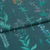 Embroidered teal fabric with vertical stitched wildflower stems — folded once across the middle, showing multicolored threadwork — close-up view with even, soft lighting emphasizing texture.