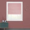 Pink Roman shade, lowered near sill with folds; partially filtering daylight; in a white-trimmed window on a dusty-rose wall above a teal dresser and gold sconce, blurred greenery outside.