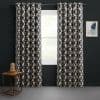 Grommet-top floor-length curtains with navy lattice pattern on cream, hung on a metal rod and parted to reveal a sunlit window, framing a bright green yard against dark-painted walls.