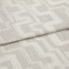 Beige woven fabric with raised cream geometric square pattern, folded in a horizontal overlap; close-up shot under soft neutral lighting, resembling an upholstery or drapery sample.