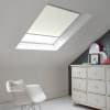 Room with white eaves wall, dark blue-grey wall to right with a shabby chic white drawer unit, a contemporary white chair, white painted floorboards and a skylight blind in opal.