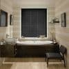Black horizontal blinds, fully closed with thin slats covering a central window; blocking daylight; above a white tub in a warm wood-paneled bathroom with sink, shelf and chair.