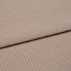 Ribbed beige corduroy fabric, folded into two layered panels showing parallel ridges, photographed close-up on a neutral surface with soft, even studio lighting.