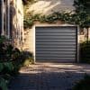 Horizontally ribbed metal roller garage door, closed and reflecting warm sunlight; set in a brick facade framed by climbing ivy, lanterns, opening onto a sunlit paved driveway bordered by plants.
