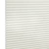 White cellular (honeycomb) blind, fully lowered and closed, its horizontal pleats visible; gently diffusing light in a neutral interior, shown in a close-up angled view.