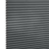 Gray cellular (honeycomb) blind, fully lowered with horizontal pleats and exposed honeycomb edges at left, blocking light; close-up studio view against a white background.