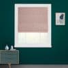 Blush-pink Roman shade inside a white window frame, partially lowered and filtering daylight. Set on a dark teal wall in a minimalist room with a dresser and framed abstract art.