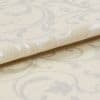 Cream damask curtain fabric swatch, folded with raised woven scroll motifs, reflecting subtle sheen; close-up macro view showing textured weave and soft studio lighting on a neutral surface.