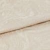 Beige jacquard fabric with subtle swirling embossed pattern, folded over itself; close-up view showing raised texture and soft sheen, neutral lighting on a plain surface.