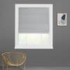 Gray fabric Roman blind fully lowered with subtle folds, filtering daylight from a white-framed window; mounted on a gray wall beside abstract framed art above a gold wire chair.