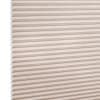 Beige honeycomb cellular blind with horizontal pleats and textured fabric, fully lowered and closed, diffusing light across a neutral, softly lit interior close-up.