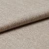 Beige woven upholstery fabric (tight basket weave), folded over an edge, displaying textured threads and slight sheen; close-up on a flat surface under soft, diffused lighting.