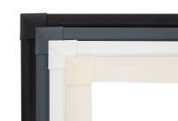 Four rectangular frame corners (black, charcoal, white, cream) layered diagonally at the top-left, overlapping to display mitered joints; photographed close-up against a bright white studio background with soft lighting.