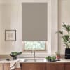 Roller blind lowered over a kitchen window, blocking light; stainless faucet and sink below on a stone countertop with wooden cabinets, potted plants, leafy vegetables, and framed sketch nearby.