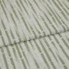 Textured upholstery fabric with vertical olive-green dashed stripes, folded once across the center creating an overlapping seam; close-up view with soft, even lighting and neutral, fabric-only background.