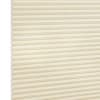Cream-colored cellular (honeycomb) blind, fully lowered and closed, pleated horizontal cells; gently filtering diffuse light against a plain, softly lit interior with no visible window frame.
