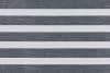 Zebra-style roller blind with alternating opaque white and semi-transparent dark-gray textured horizontal bands; bands aligned to create alternating blocked and filtered light; covers a window in a neutral, evenly lit interior.